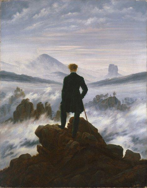 Man standing on a rocky cliff overlooking a vast sea of fog and mountains, symbolizing solitude, reflection, and perspective
